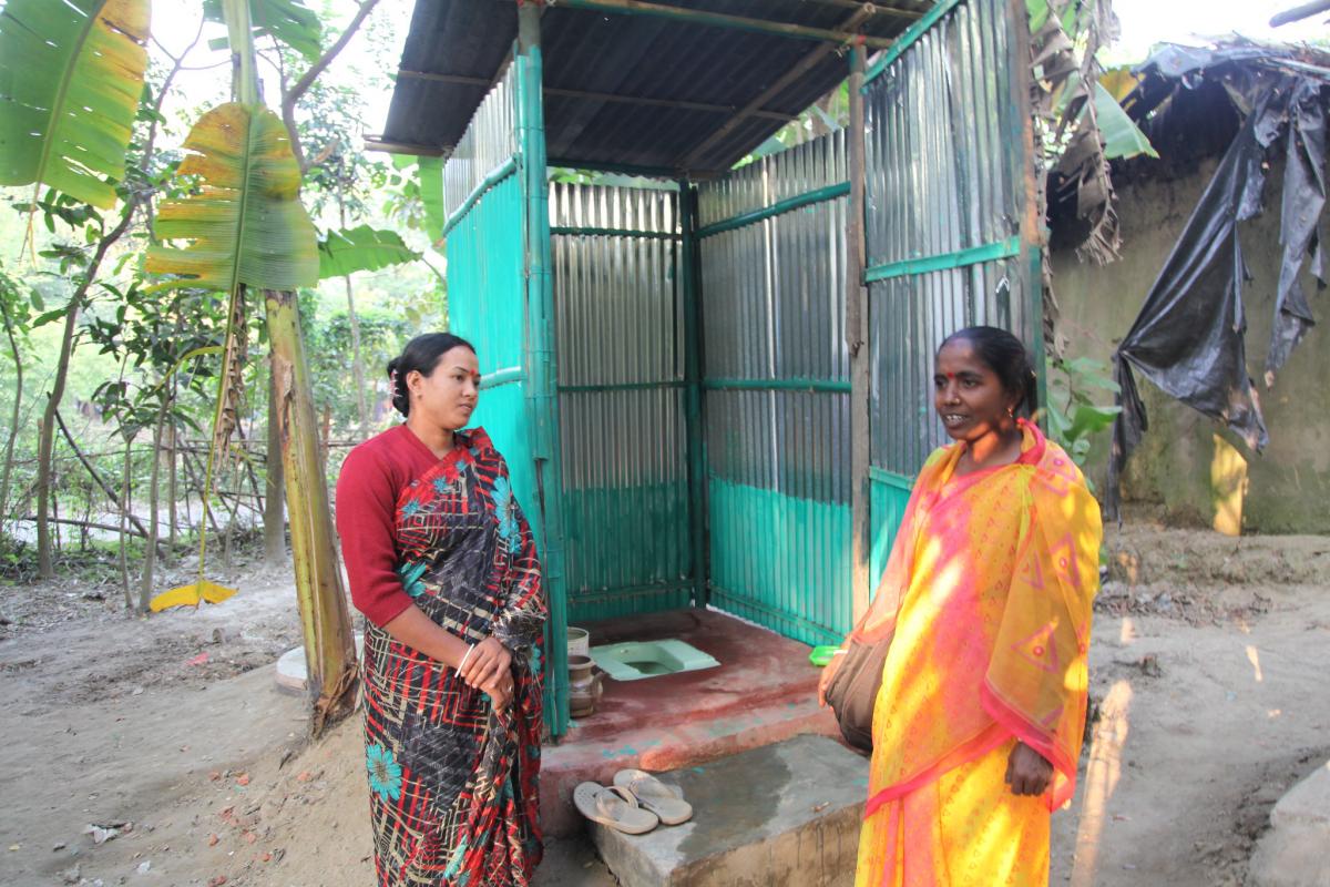 Fieldworker inspects village latrine in Mujaffarabad, Chittagong, Bangladesh