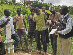 Martin Watsisi (left), talks to community members at Magura shallow well in Karambi sub-county